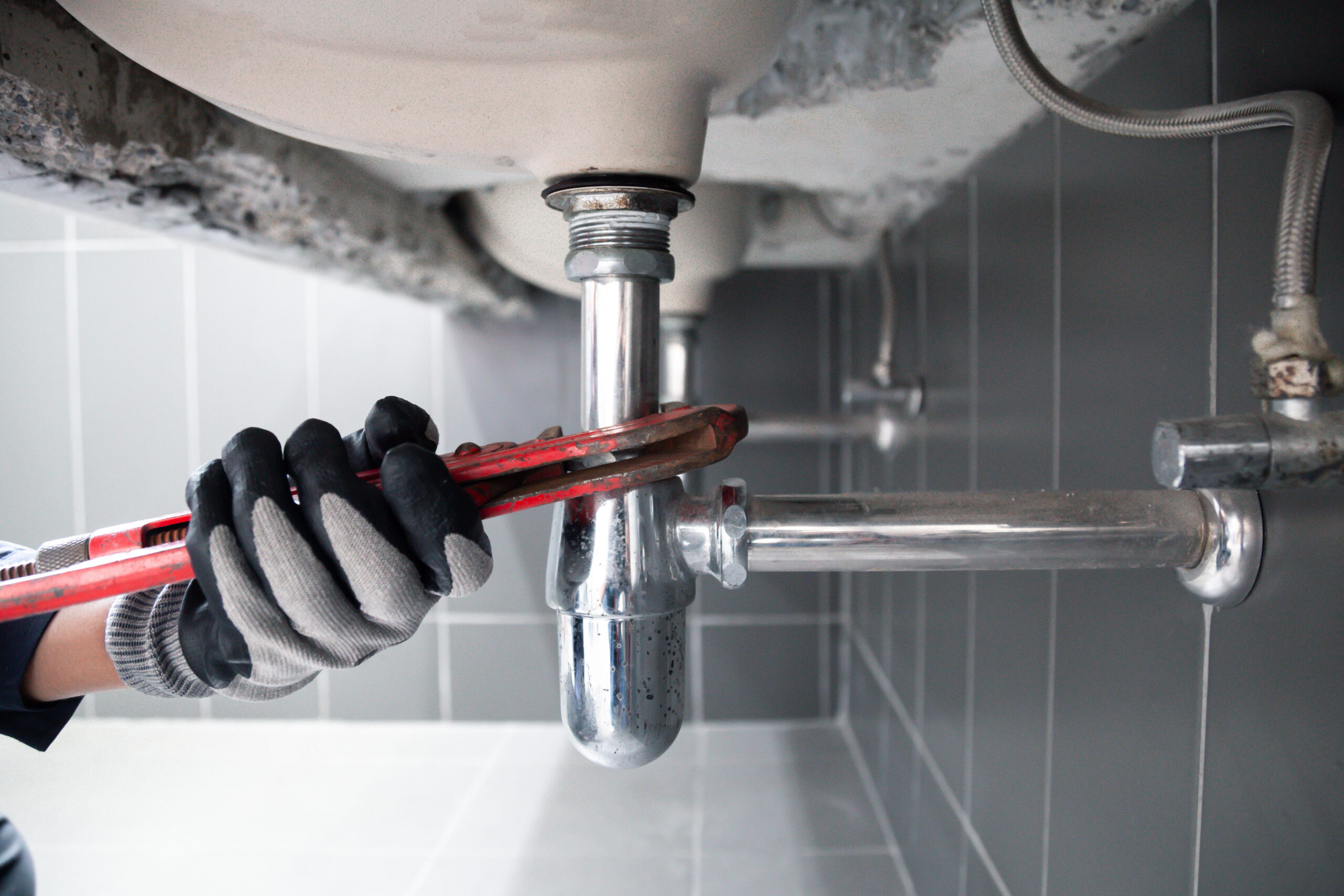 Plumber using a wrench to repair a water pipe under the sink. Concept of maintenance.specialist male plumber repairs faucet in bathroom.